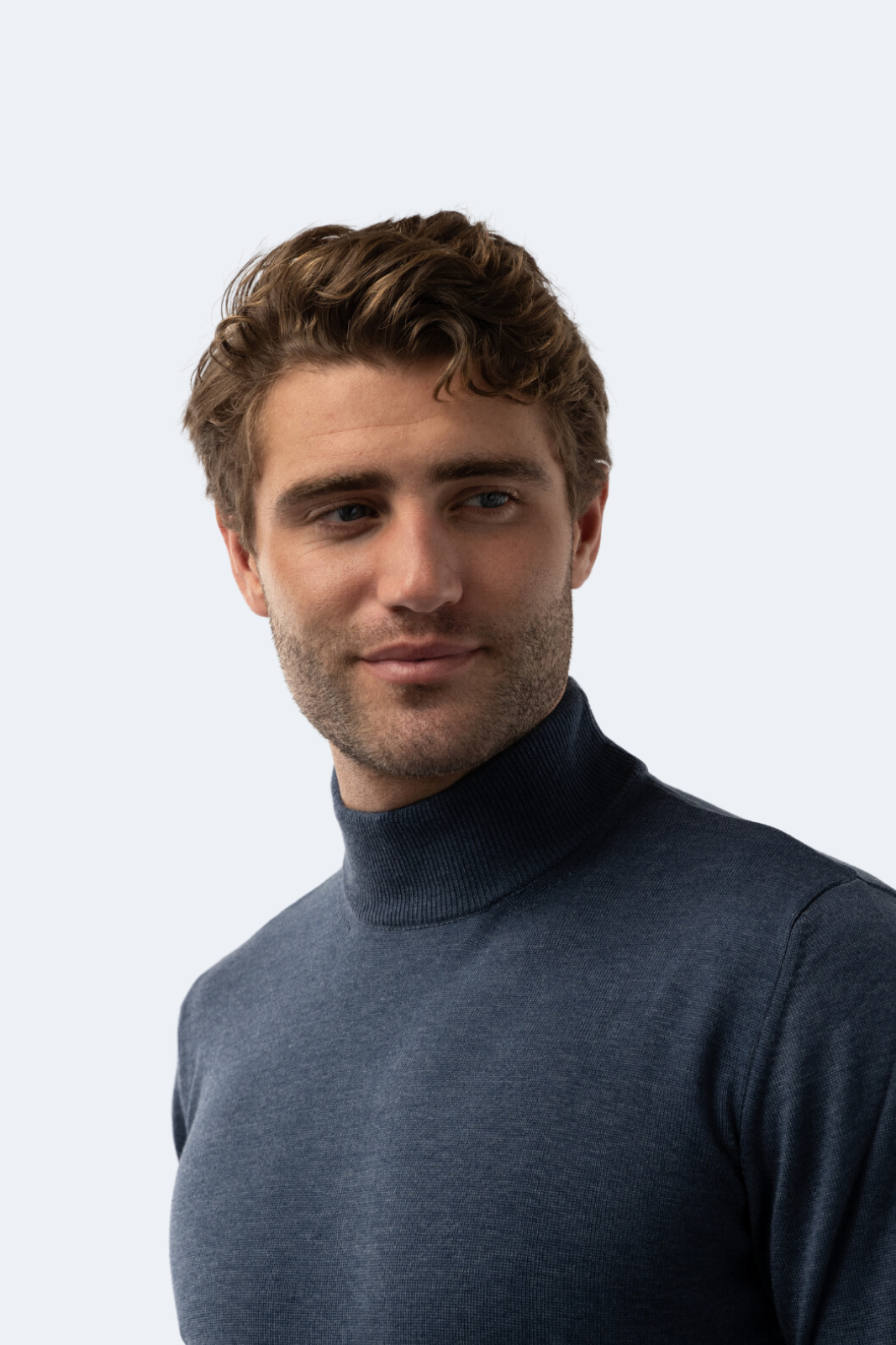 Man wearing a blue mock neck sweater against a light gray background