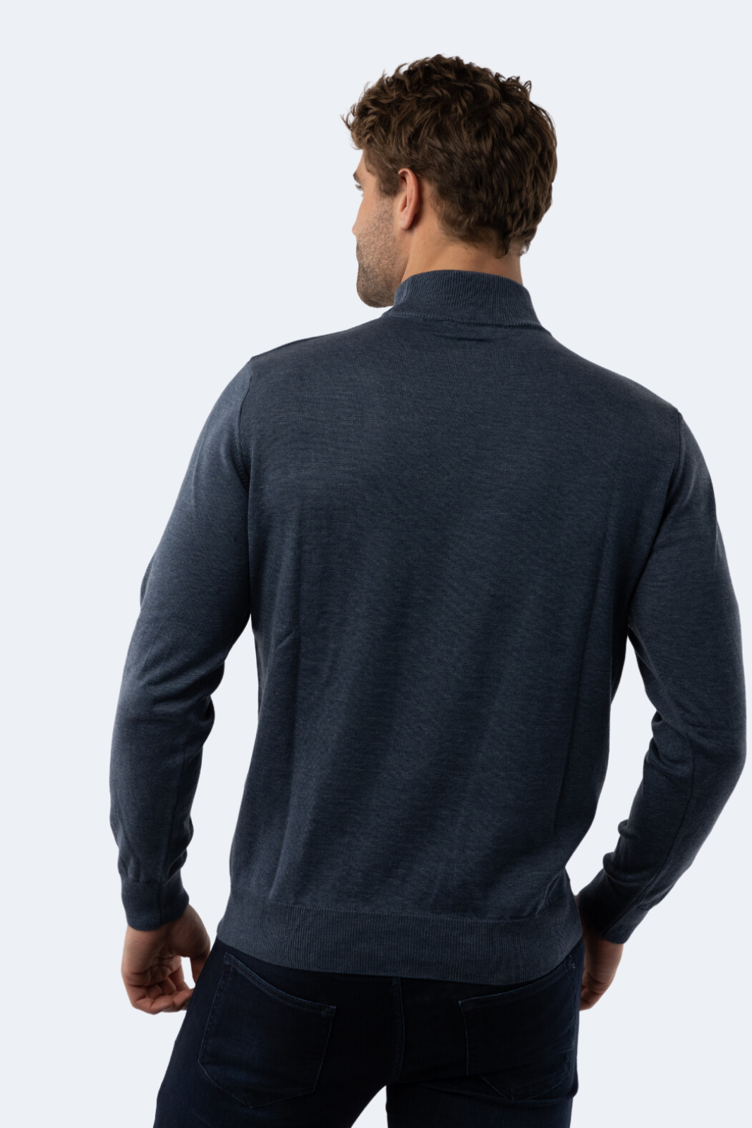 Man wearing a dark blue mock neck sweater against a white background