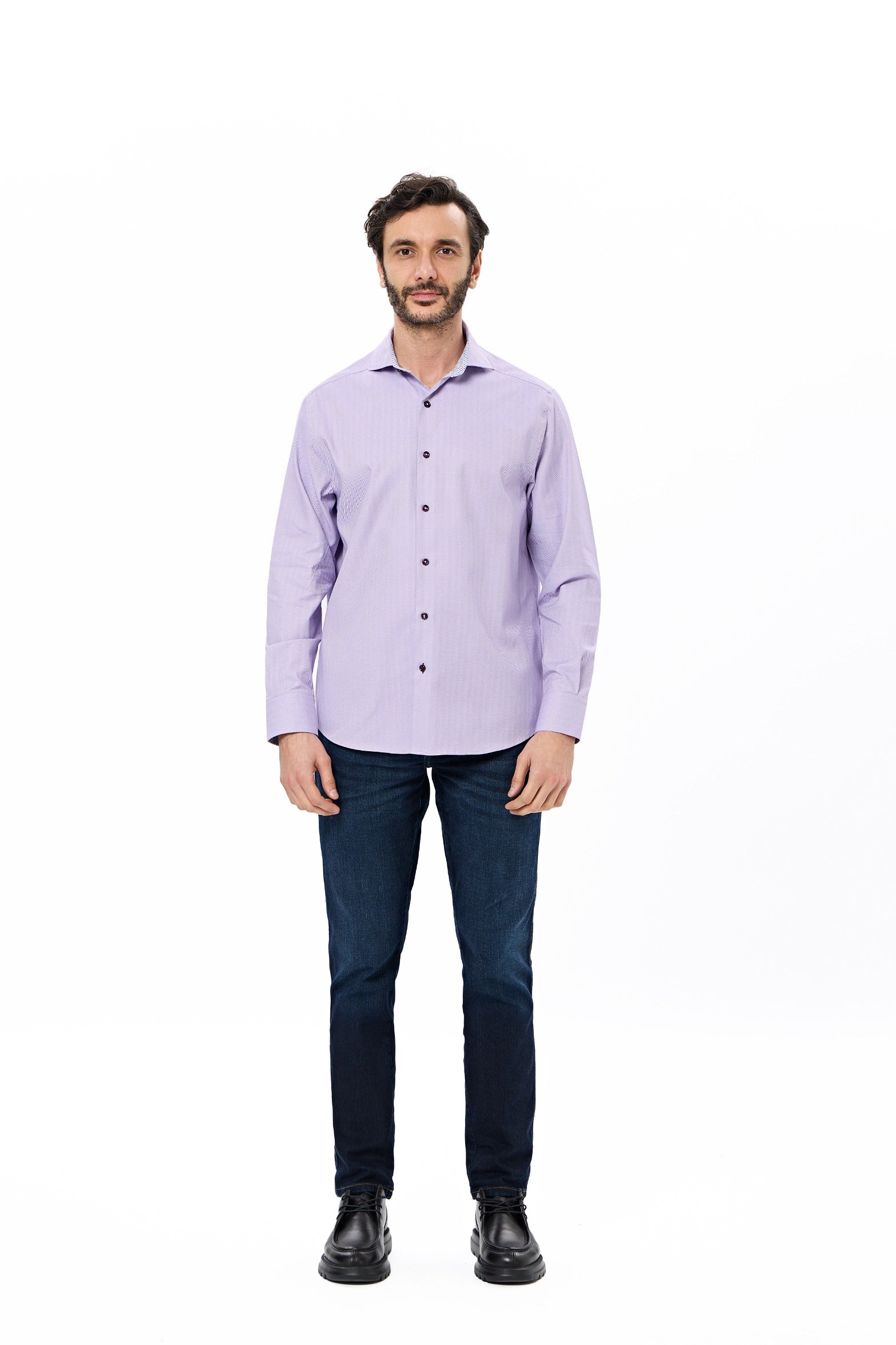 Man wearing a light purple shirt and dark jeans on a white background
